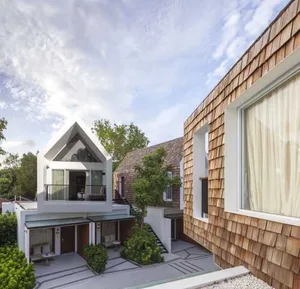 A modern residential exterior with wooden shingles and large windows.