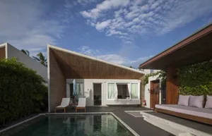 Modern residential exterior featuring a sleek wooden structure with a pool area and outdoor seating.