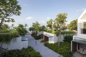 An aerial view of a modern residential house with a green roof and surrounding landscaping, under a clear blue sky.