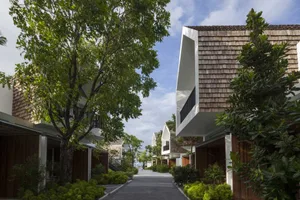 A modern residential exterior with wooden structures, glass doors, and concrete walkways.