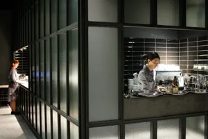 A modern restaurant interior featuring glass walls and stone surfaces.
