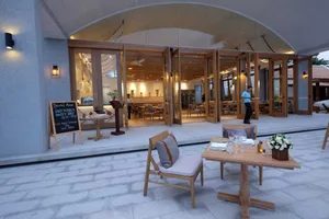 Modern restaurant interior with wooden furniture and open doors to dining area
