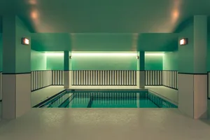 An image of a modern indoor swimming pool with tiled concrete walls.