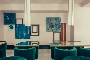 A room with modern metallic furniture and art installations, viewed from above.