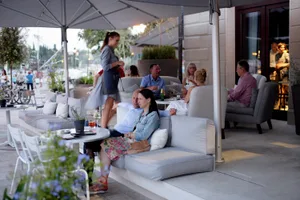 An outdoor seating area of a restaurant with fabric furniture and urban surroundings.