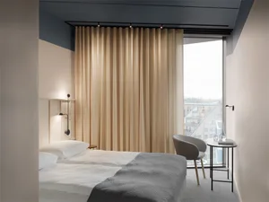 Minimalist bedroom with gray furnishings and a ceiling light fixture.