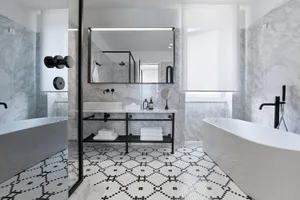 A modern bathroom with marble walls, mosaic floor tiles, and a freestanding bathtub.