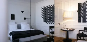 A modern bedroom featuring black and white decor, with a bed, bench, and lamp.