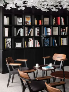 A modern library space with wooden chairs and a large bookshelf filled with books.