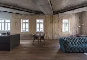 A modern living room with exposed concrete walls and a blue upholstered sofa.