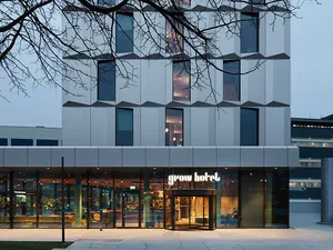 Modern hotel building with concrete exterior and glass doors.
