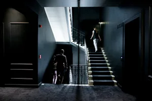 A modern hotel staircase with metal railings and black walls.