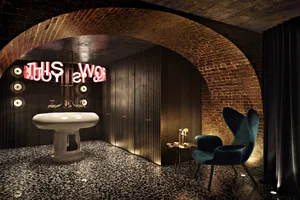 Industrial-style bathroom with brass fixtures and illuminated red text above the sink.