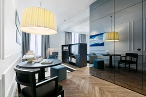 Modern living room with white walls, wood floor, and blue seating.