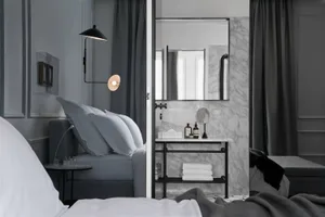 Modern minimalist bedroom with dark gray curtains, marble bathroom, and metal accents.