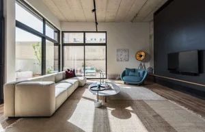 A modern minimalist living room with large windows, concrete and glass surfaces, and a wooden floor.