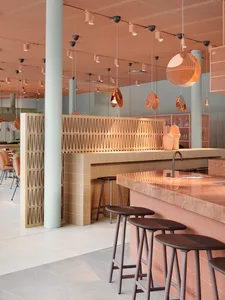 A modern restaurant bar with marble and concrete finishes and a minimalist design.