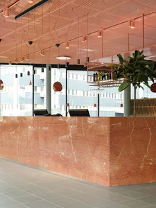 Modern restaurant interior featuring a polished marble counter with seating and decorative elements.