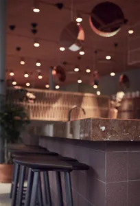 Concrete bar top with industrial lighting and seating.