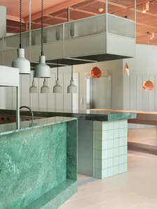 Modern restaurant interior with green marble countertop and white tiled wall