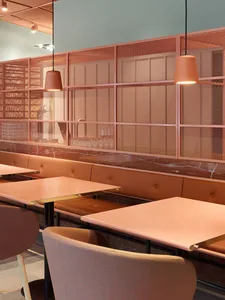 A modern restaurant interior with a unique design featuring a mesh partition made of metal rods and a marble counter top.