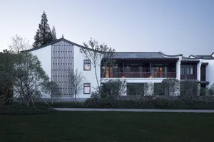 一棟現代簡約住宅，擁有白色粉刷牆面、混凝土屋頂及木瓦屋頂。