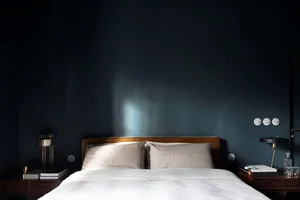 A minimalist bedroom with a white bed and blue accent wall