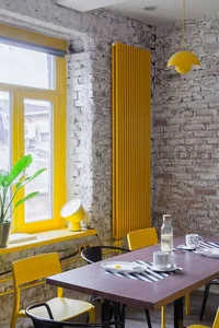 Industrial-style breakfast nook with exposed brick walls and yellow metal chairs and radiator