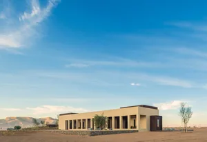 A minimalist building exterior with a desert landscape in the background.