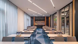 Conference room with modern design featuring concrete walls, glass partition, metal tables, and fabric-covered chairs.
