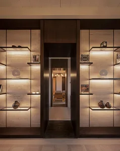 A modern entrance featuring a minimalist design with concrete floating shelves and dark wood accents.