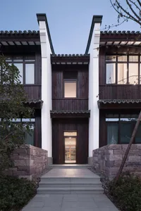 A modern exterior of a house composed of wooden and stone materials with large windows and a tiled roof.