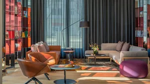 A contemporary living room with modern furniture, a mix of materials, and large windows.