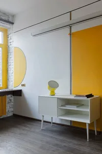 A modern living room with white furniture and a yellow accent wall