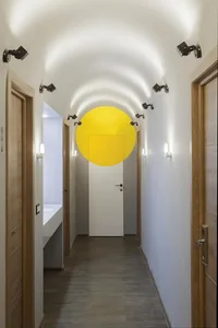 A modern minimalist corridor with a yellow circle on a white door.