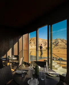 A modern restaurant interior with concrete, glass, and stainless steel elements.
