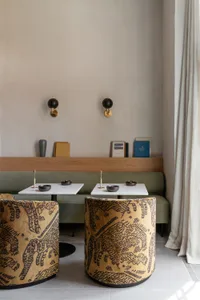 A cafe interior featuring patterned sofas, a concrete countertop, and a wooden bench seating area.