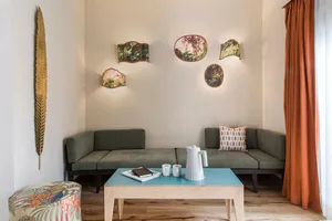 A modern living room with a green sofa, decorative wall plates, and a blue coffee table.