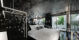 Modern bedroom featuring metallic tiles with black accents, white bedding, and large windows overlooking greenery.