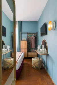 A minimalist bedroom with blue walls, wooden furniture, and a hanging wardrobe.