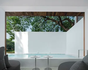 A minimalist poolside lounge featuring concrete walls and a small pool.