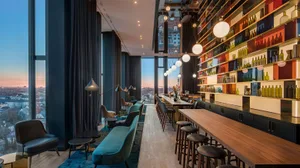 A modern restaurant-bar with a wooden counter, leather seating, and glass bottles.
