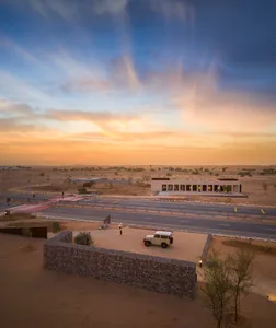 A desert landscape with a roadway and a building at sunset.