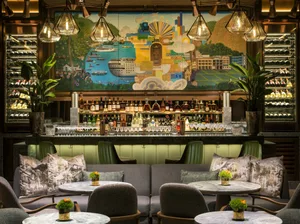 Modern industrial bar with large mural depicting cityscape and wine racks.