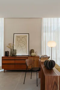 A minimalist living room featuring wooden furniture, a floor lamp, and modern decor elements.