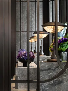 A modern hotel lobby featuring marble surfaces and metal accents with a bouquet of purple flowers on display.