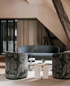 A modern living room with grey upholstered furniture, patterned chairs, and a marble coffee table.