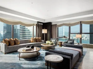 A modern living room with marble walls and flooring overlooking a cityscape.
