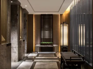A modern lobby with marble flooring and walls, featuring a bench area with plants.