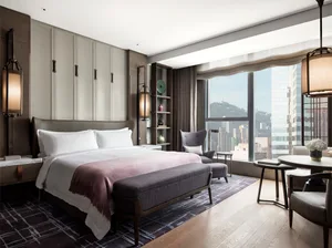 Modern, luxurious bedroom featuring a king-sized bed with a city view through large windows.
